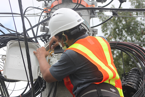 A technician servicing a fiber optic wiring on a utility pole.